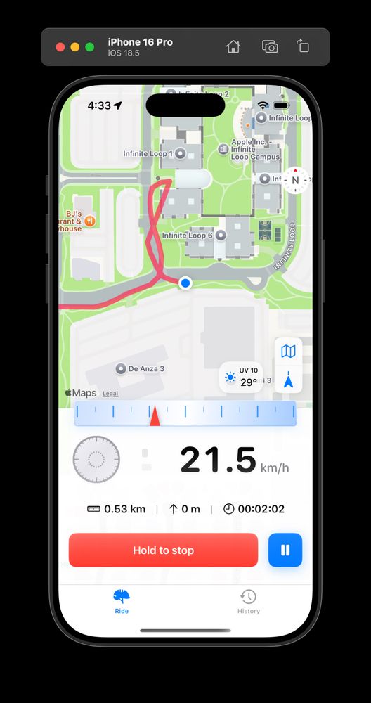 A screenshot of an iPhone 16 Pro running iOS 18.5, displaying a cycling app in ride-tracking mode. The map shows the user’s route in red around Apple’s Infinite Loop campus in Cupertino, with a blue dot indicating the current location. The app interface shows a speed of 21.5 km/h, distance of 0.53 km, zero elevation gain, and ride duration of 2 minutes and 2 seconds. A UV index of 10 and temperature of 29°C are displayed. At the bottom, there are buttons to pause or stop the ride, and tabs for “Ride” and “History.”