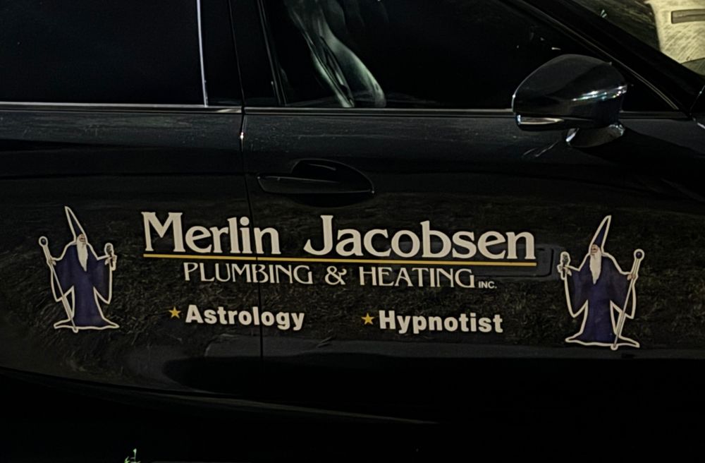 The side of a car advertising a plumbing and heating company along with astrology and hypnotism. 