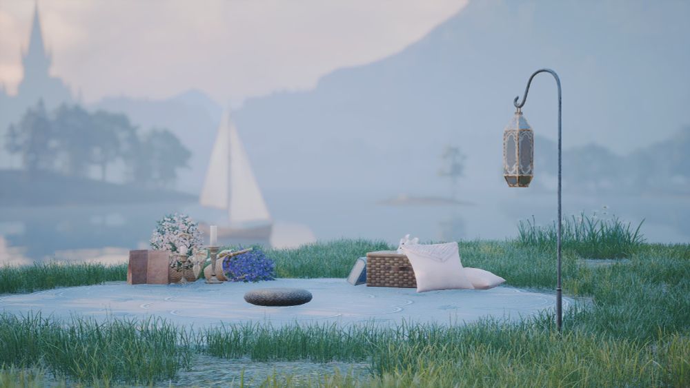 A blanketed picnic area - a blue rug, white pillows, and a small lantern all surrounded by vibrant green glass. A white sailboat floats on water in the background. 