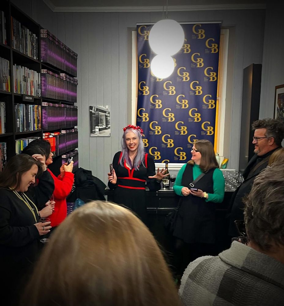 A K Benedict and crowd smiling during her speech at the launch of Little Red Death at Goldsboro bookshop 