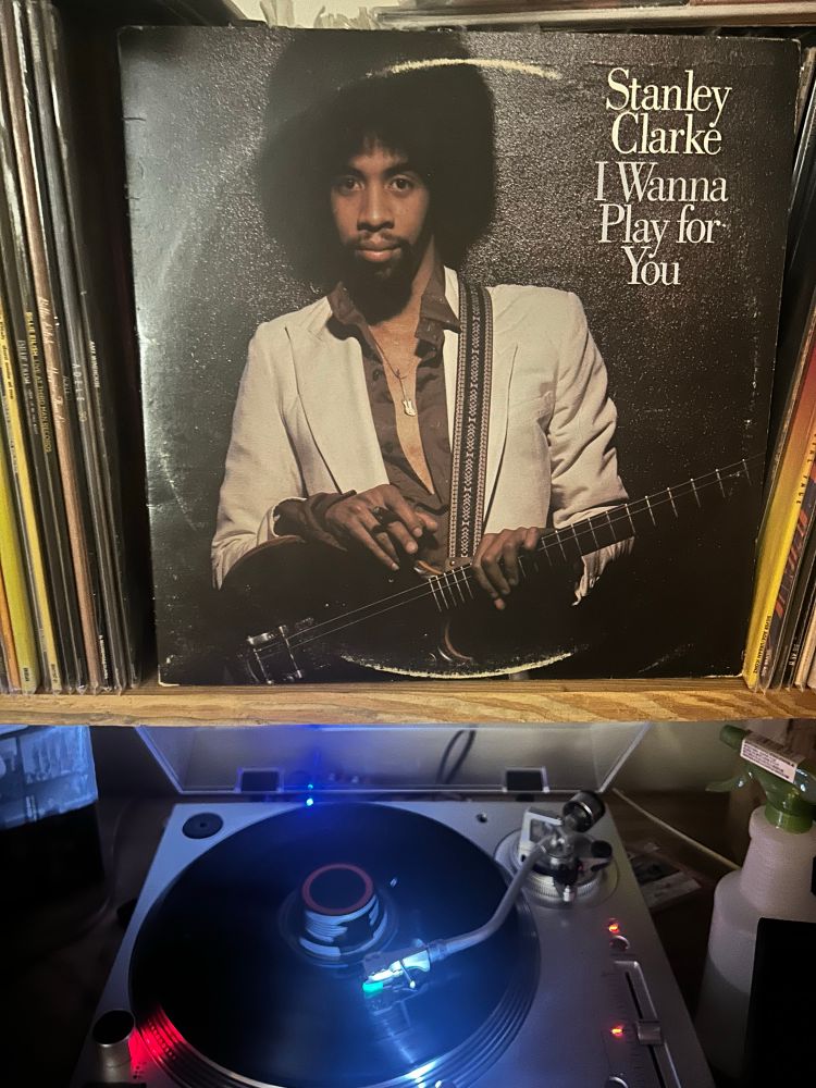 Image of Stanley Clarke: I Wanna Play for You record cover above the turntable. 