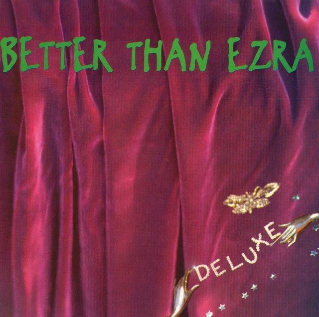 Fuchsia curtain with words “Better Than Ezra” in green and “Deluxe” in bottom right corner.

