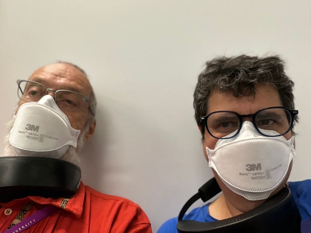 Man and women wearing N95 masks and portable air purifiers around their necks. 