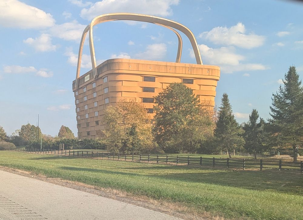 A photo of a giant basket on the side of the road. The basket is actually the former headquarters building for the Longenburger Basket Company. It's in the shape of one of their baskets, complete with handles.