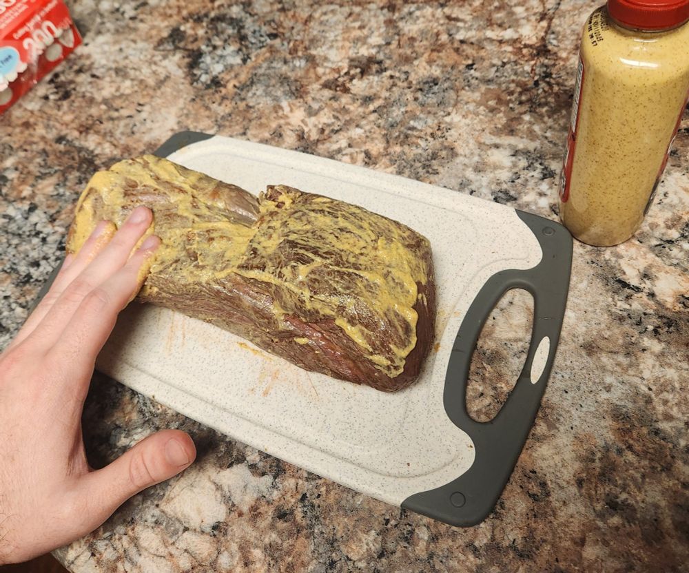 a seared beef tenderloin getting rubbed down with Dijon mustard 