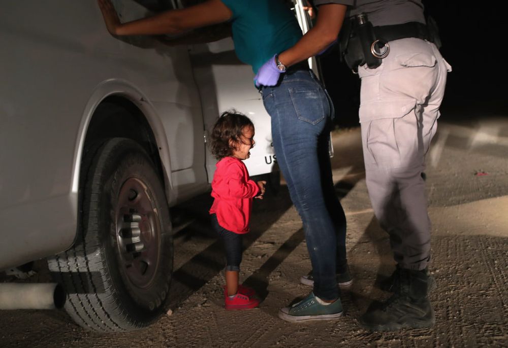 Young child crying while mother is frisked by a federal agent at the US Border
