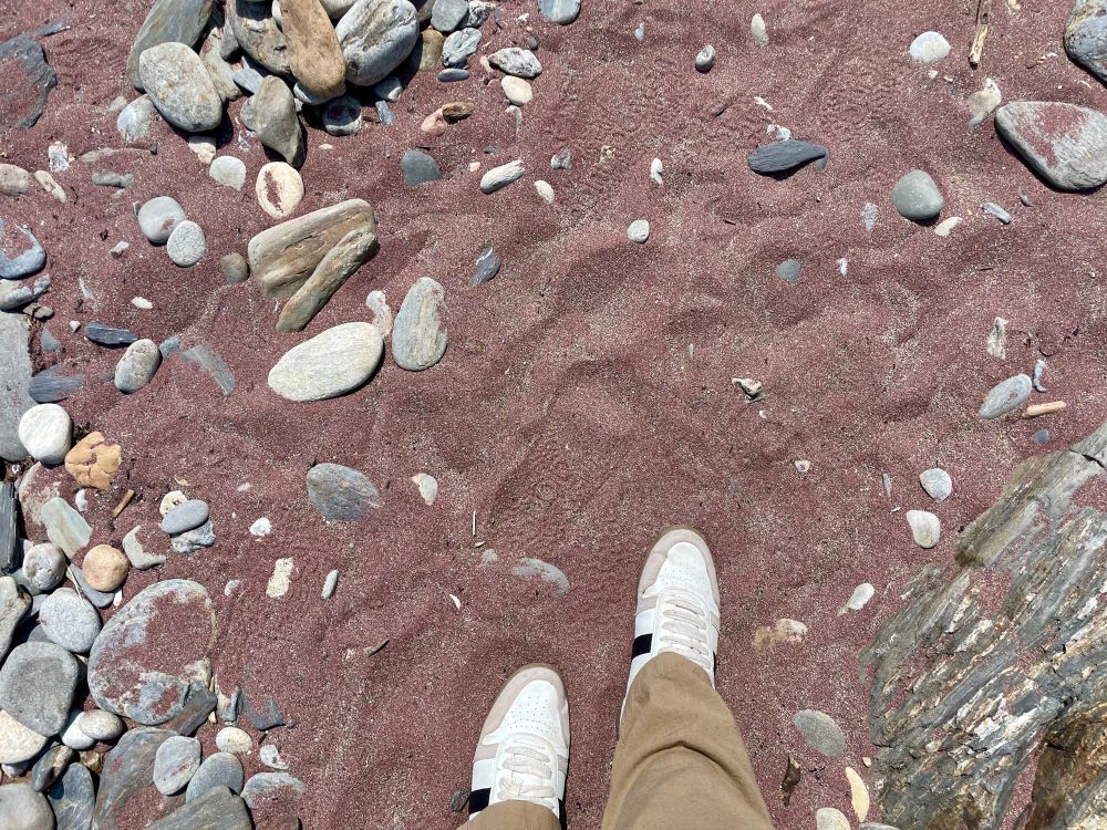 Sneakers on red sand with lots of smooth rocks around