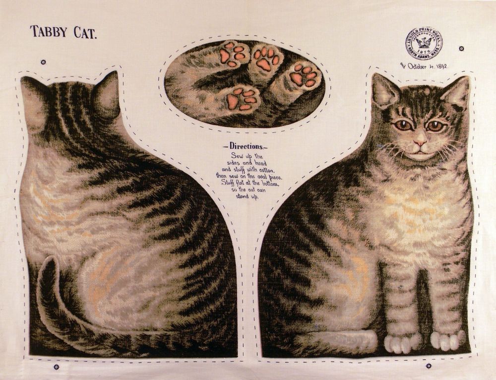 “This roller-printed heavy cotton ready-to-sew doll was one of several patented by Arnold's.”
ready-to-sew grey tabby cat doll in three cut-out parts (front, back, bottom/feet), with instructions printed on cloth: “Sew up the sides and head and stuff cotton, then sew on the oval piece. Stuff flat at the bottom so the cat can stand up.”