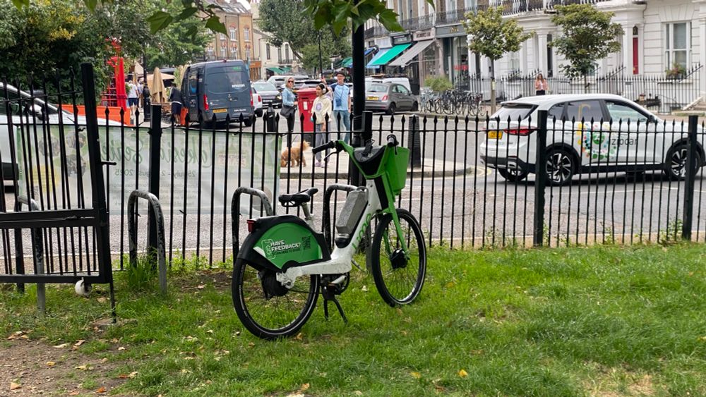 Lime bike next to the cycle parking on the edge of the park.