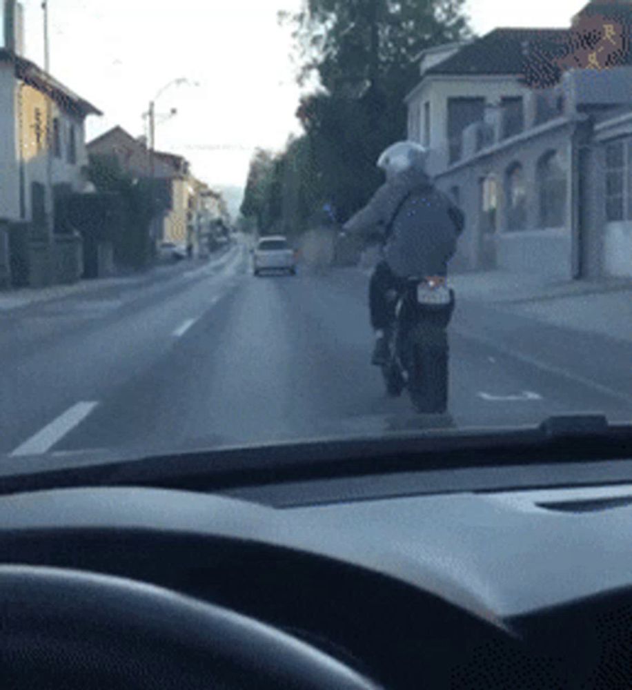 a man is riding a motorcycle down a street with a license plate that says ' jc ' on it