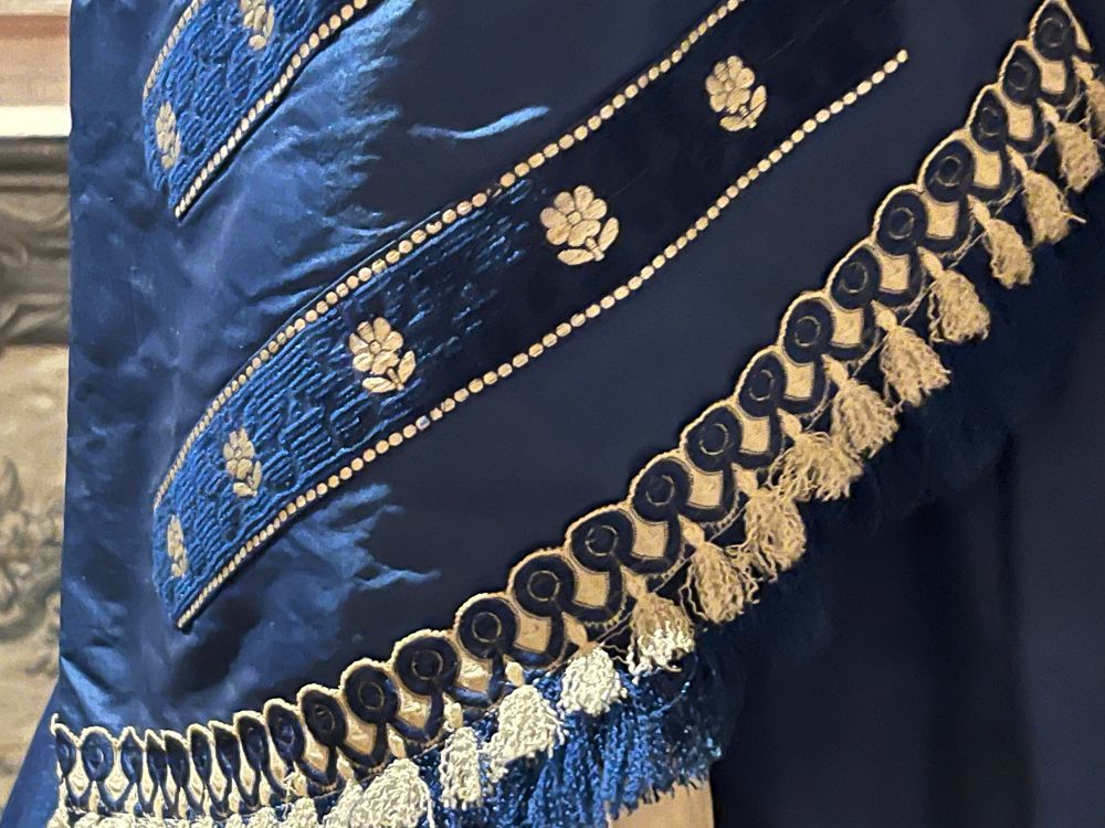A close up of an 1860s dress sleeve. Showing tassels and hand embroidered flowers. Photo by Robert Emond. 