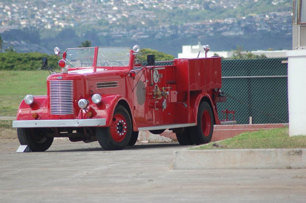 A vintage fire truck on the tarmac of the Pearl Harbor Aviation Museum. Honolulu is visible in the background. Photo by Robert Emond. 