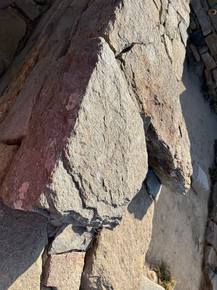 A moody photo of ancient rock stone wall on the island of Delos. The photo is shot at a Dutch angle.  One face of the wall sparkles and shines in the light. The other side is in shadow. It is fitting as Delos is the birthplace of Apollo, the god of light, harmony, and balance, and his twin sister Artemis, the moon-goddess. Photo by Robert Emond. 
#PhotographersUnited
#FineArtPhotography 