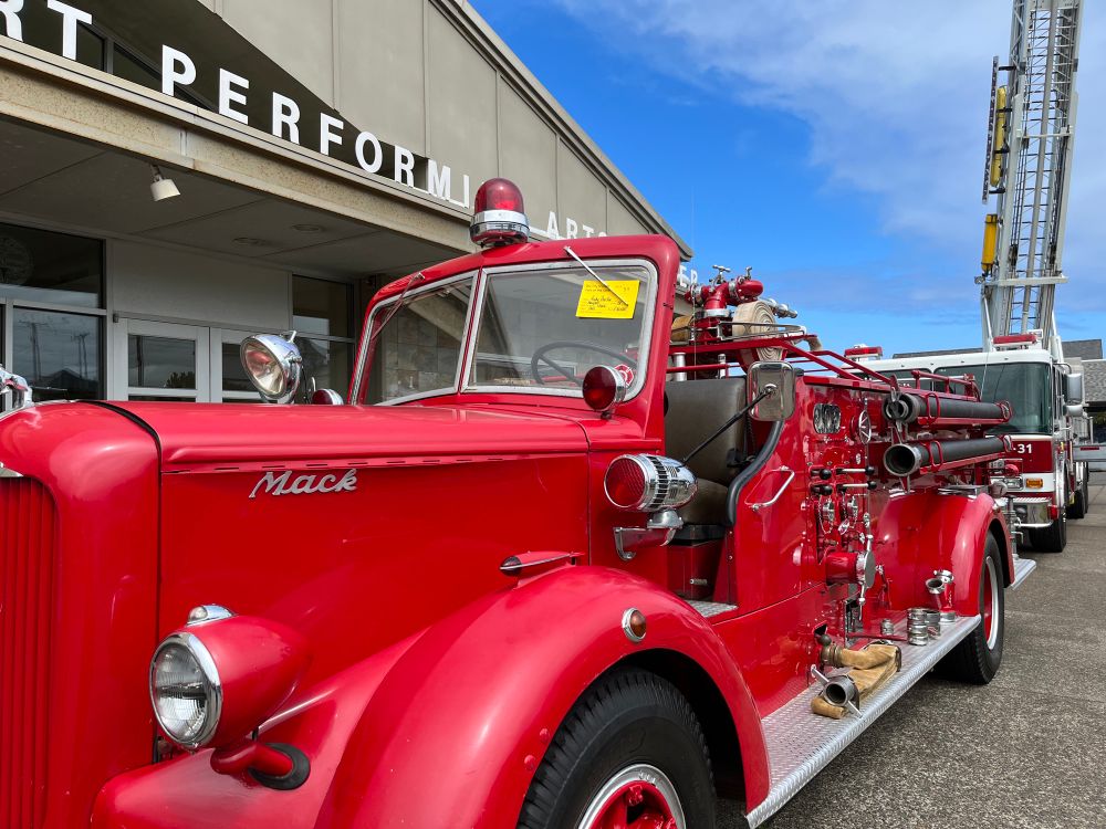 A vintage mid-century Mack fire engine with a more modern hook and ladder engine behind it. Photo by Robert Emond. 