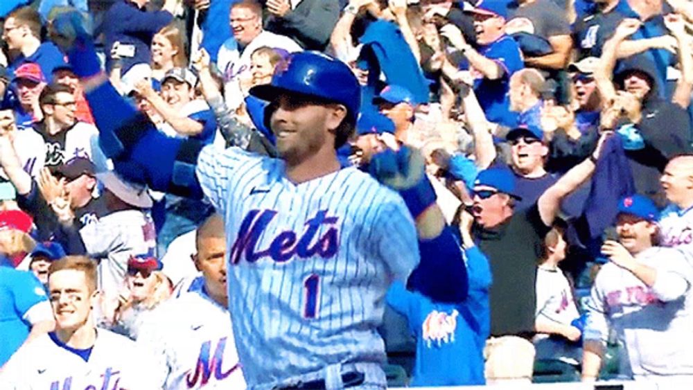 a mets baseball player stands in front of a crowd of fans