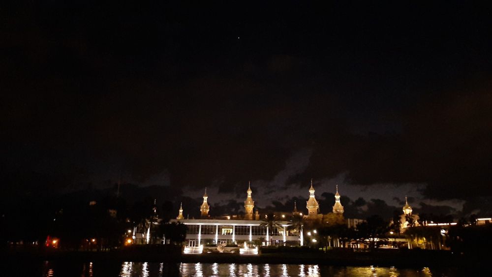 A light covered University under the darkness of night with a planet shining above.