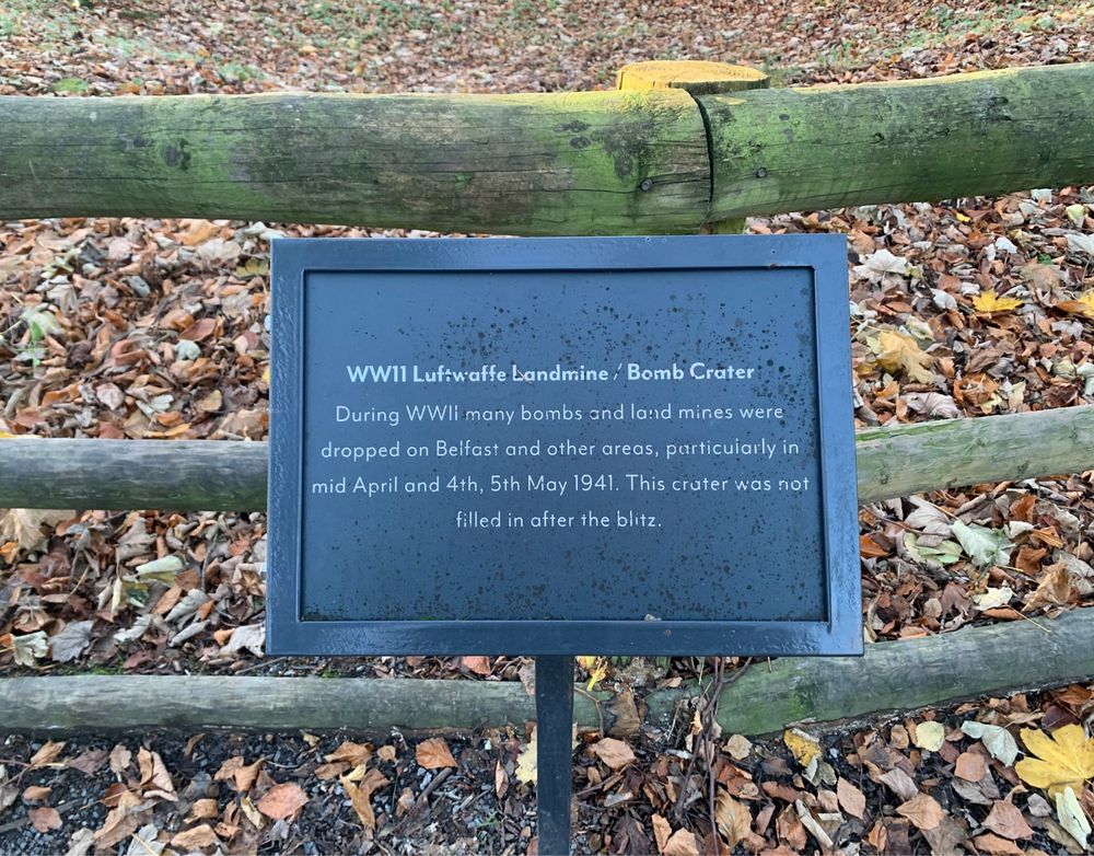 Explanatory marker on the grounds of the Stormont Estate, Belfast. The marker reads: ‘WWII Luftwaffe Landmine / Bomb Crater. During WWII many bombs and land mines were dropped on Belfast and other areas, particularly in mid April and 4th, 5th May 1941. This crater was not filled in after the blitz’.