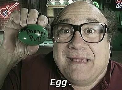 a man wearing glasses is holding a green egg with the words `` paddy 's pub '' written on it .