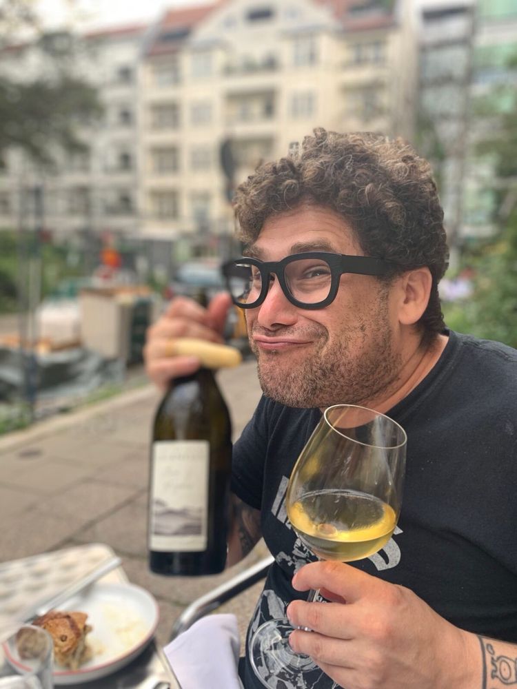 Doofus enjoys wine near park, wears chunky black spectacles