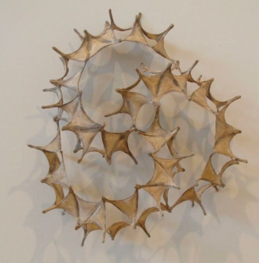 Beige fiber art sculpture with triangular shapes in a swirl