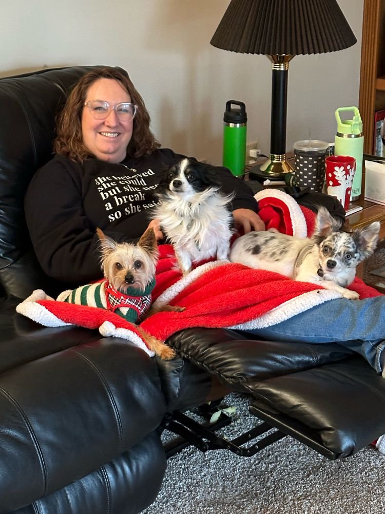 Sitting on couch holding three dogs with holiday red blanket