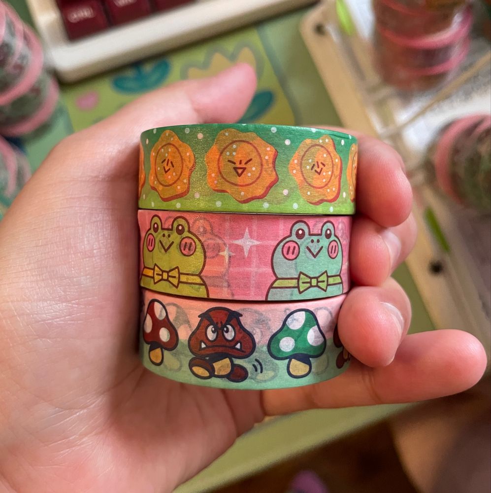 Photo of my three new washi tapes in hand, one Tostonio, one Frogs with Bow ties, one Mushroom March featuring Goombas, Super Mushrooms and 1up Mushrooms 