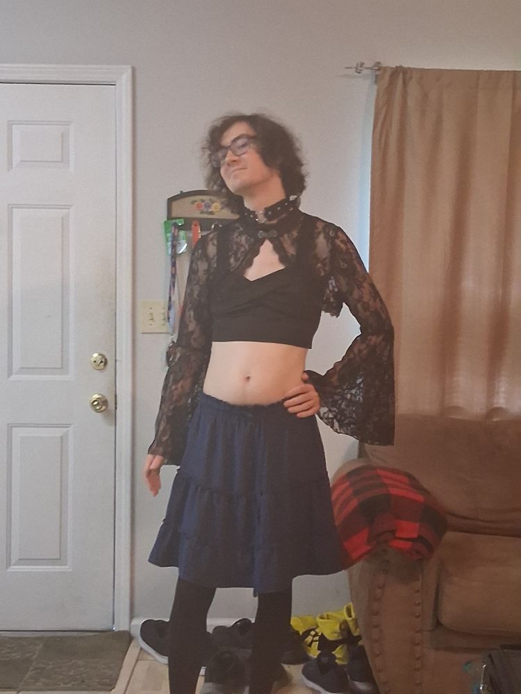 Trans lady in a black crop top and lacy cover sleeves and heart choker mixed with skirt and black tights.
pose 2