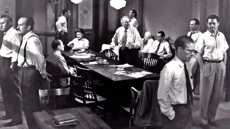 A scene from 12 Angry Men where the other jurors isolate the racist Number 10. 