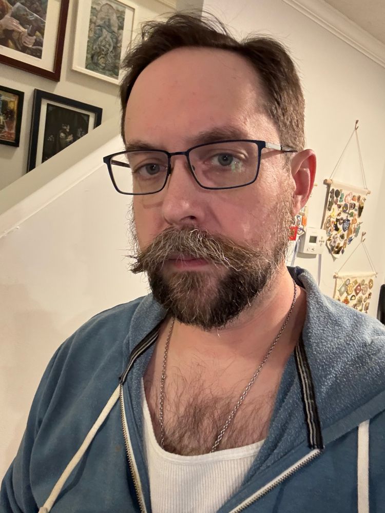 A white nerd with a beard and glasses and a haircut