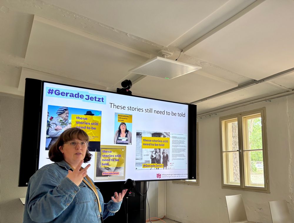 Clara in der Auswertungssession zu #geradejetzt zeigt etwas mit Händen und steht vor einer Projektion 