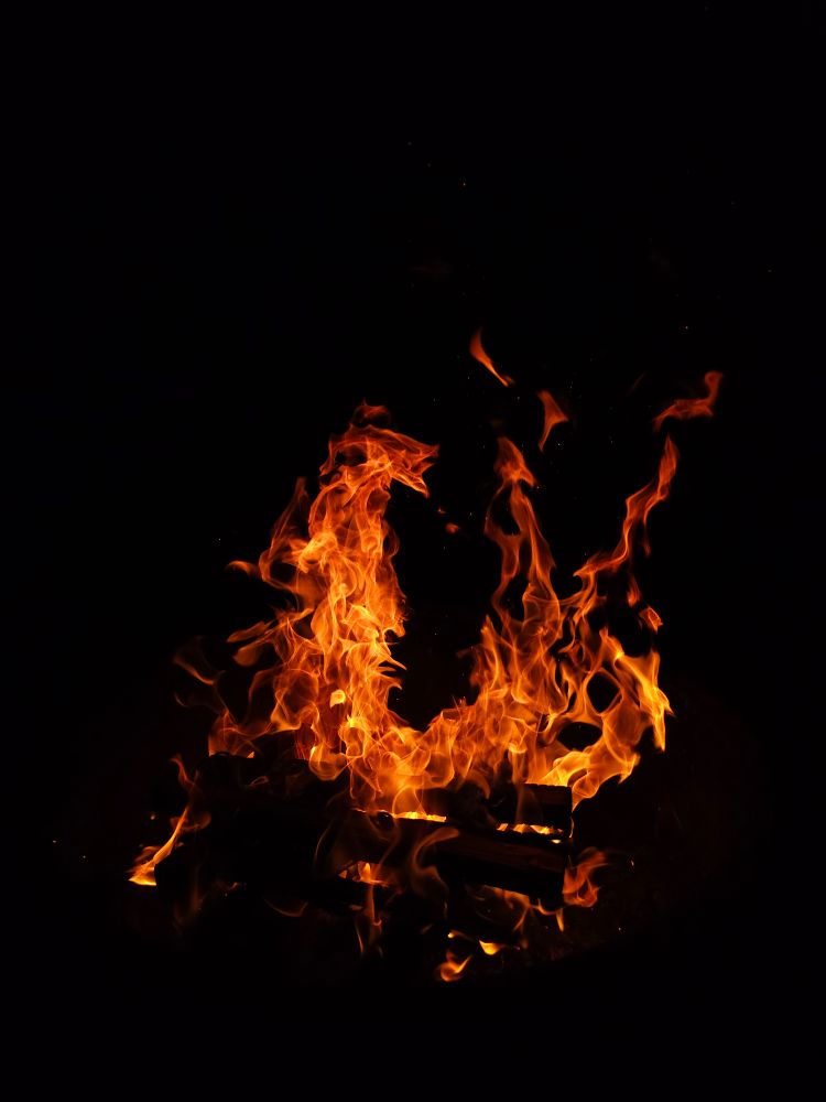 A roaring campfire against the black night sky