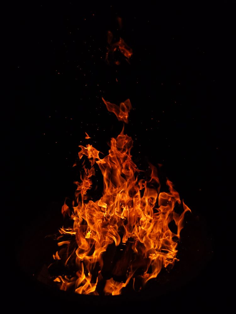 A roaring campfire against the black night sky