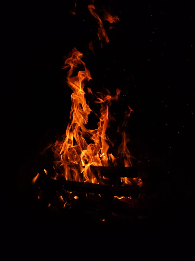 A roaring campfire against the black night sky