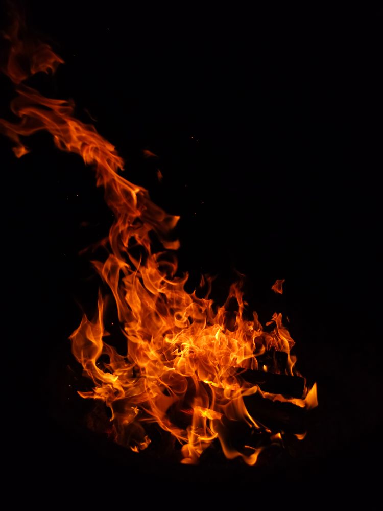 A roaring campfire against the black night sky