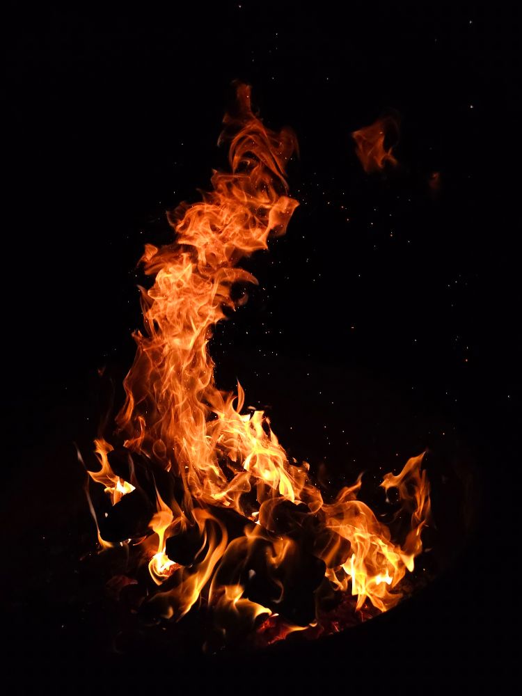 A campfire flickers and arches against the night at a campground in Washington 