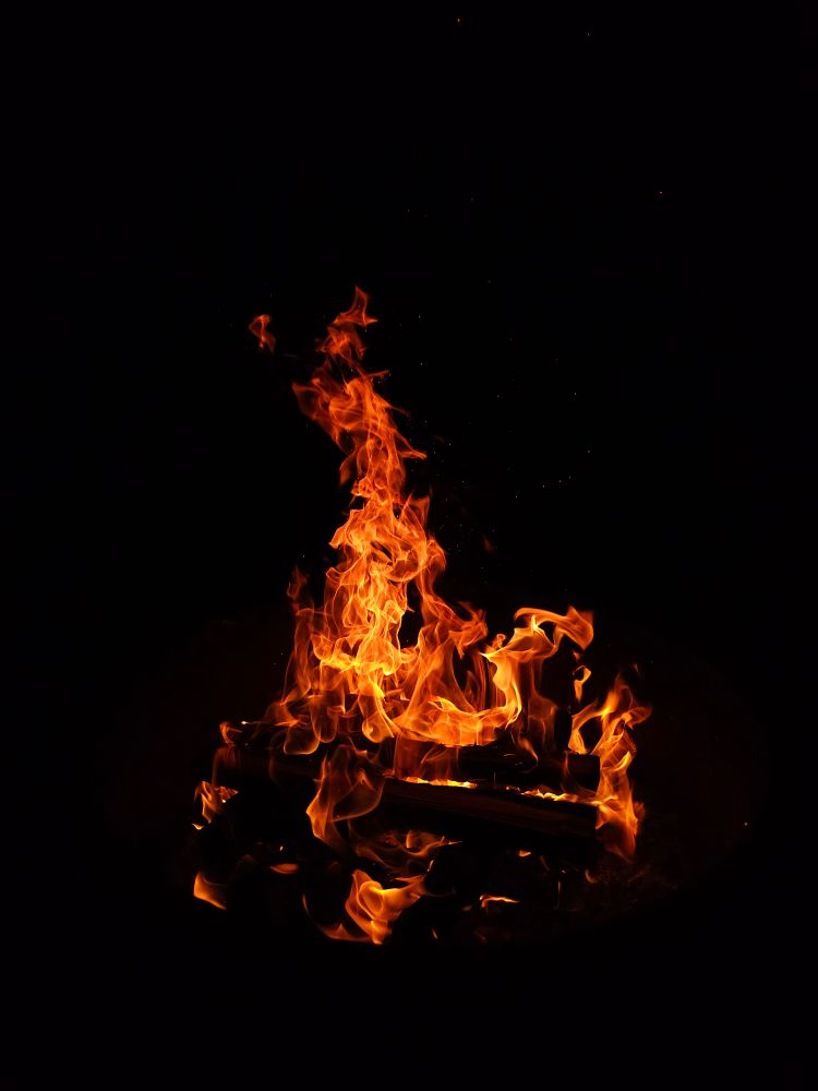 A roaring campfire against the black night sky