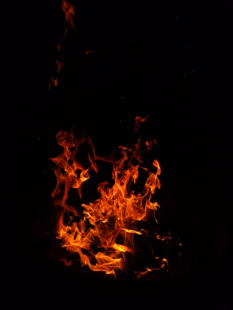 A roaring campfire against the black night sky