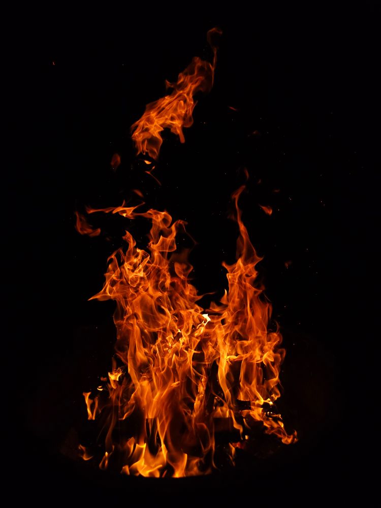 A roaring campfire against the black night sky