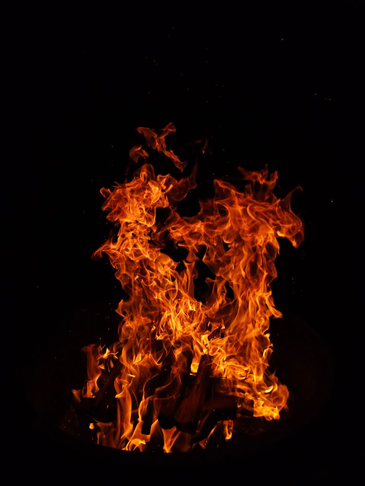 A roaring campfire against the black night sky