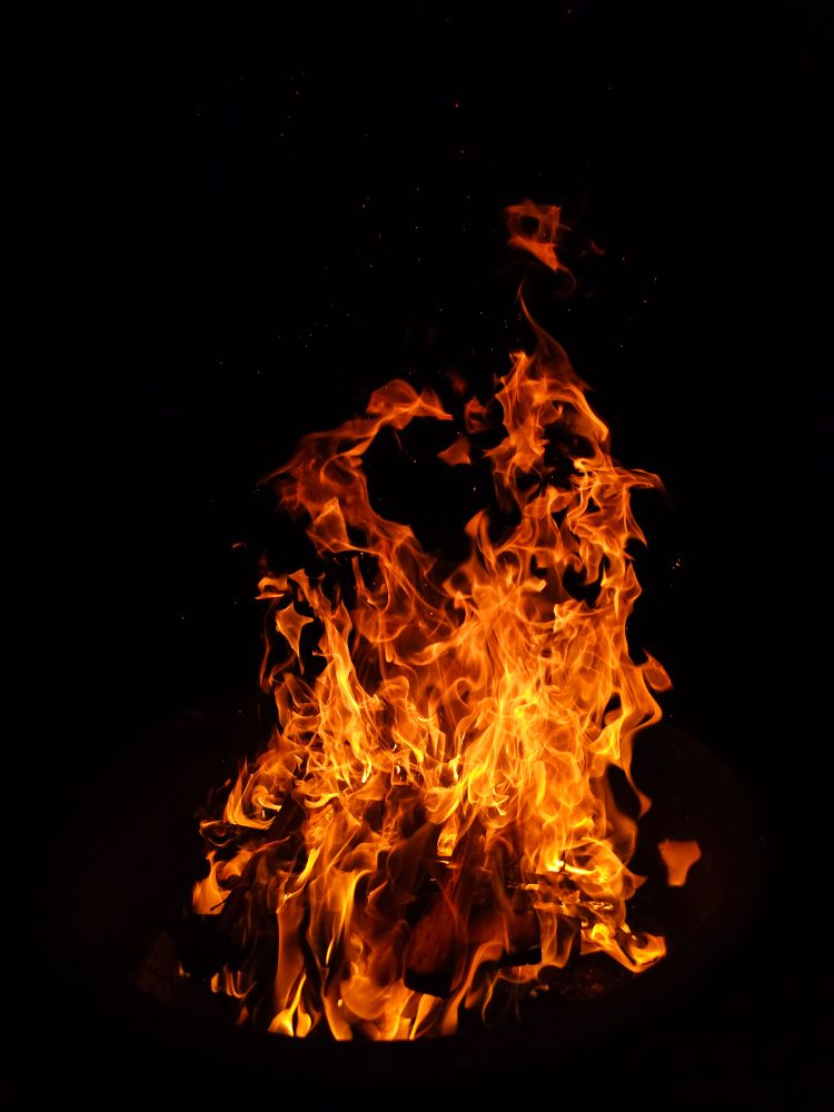 A roaring campfire against the black night sky