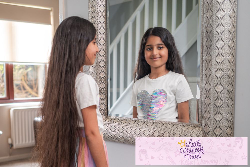 Photo of young girl looking into a mirror so you can also see the length of her hair.