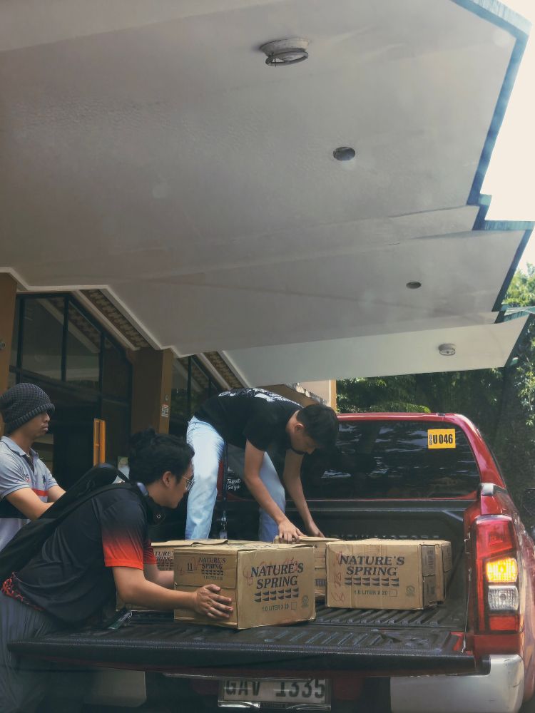 photo of people carrying boxes of aid, loading them unto a truck