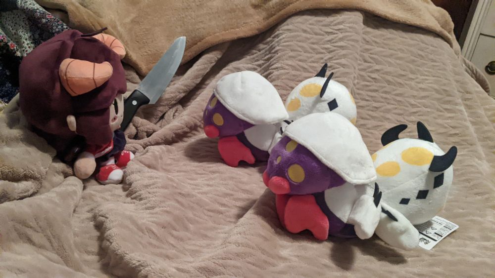 An profile image of demilypyro the vtuber but in the form of a plushie squaring off against two Rakna-Kadaki plushies while holding a great sword that looks like a common french knife.