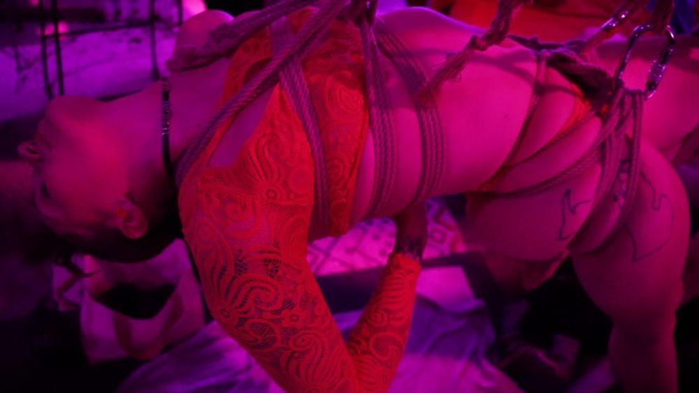 Clpser shot of Vee tied up in a Shinju Harness and Leto hip harness. Her leg is also tied, suspended off the ground. 