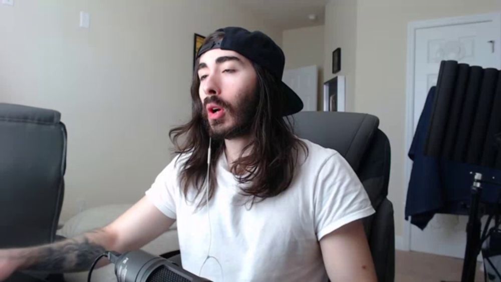 a man with long hair and a beard is sitting in front of a logitech microphone