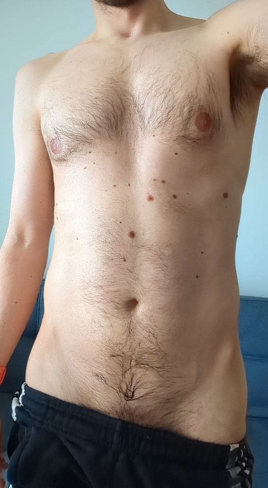 Picture of naked torso, showing a slightly hairy chest. The pants are pulled down on one side, revealing a little pubic hair
