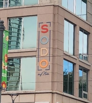 A sign on a high rise building with the name "SODO on Main." The letters "S O D O" are large and aligned vertically, with the "with Main" part positioned underneath in such a way that it makes it look like it reads "Sodom."