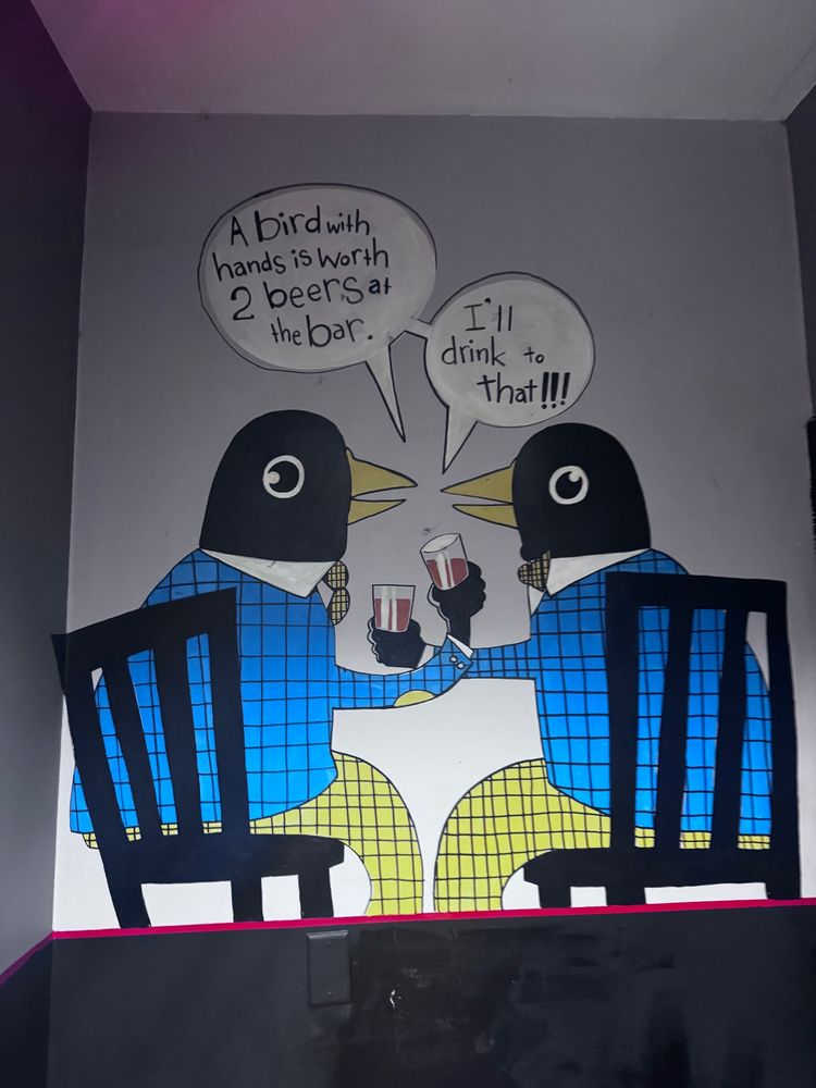 Two birds in blue jackets and yellow pants with ties cheersing 

“A bird with two hands is worth two beers at the bar”

“I’ll drink to that!”