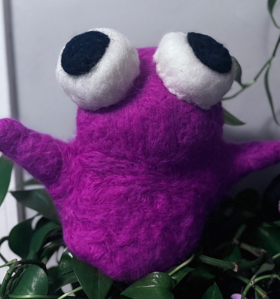 A pink felted frog with big eyes