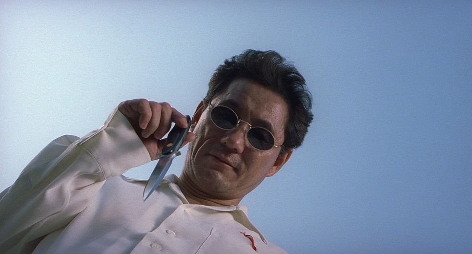 Upwards angle of a man wearing sunglasses holding a knife. 
